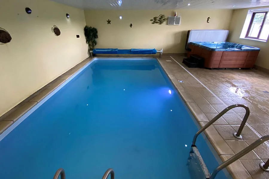 Indoor pool and hot tub in well-lit room
