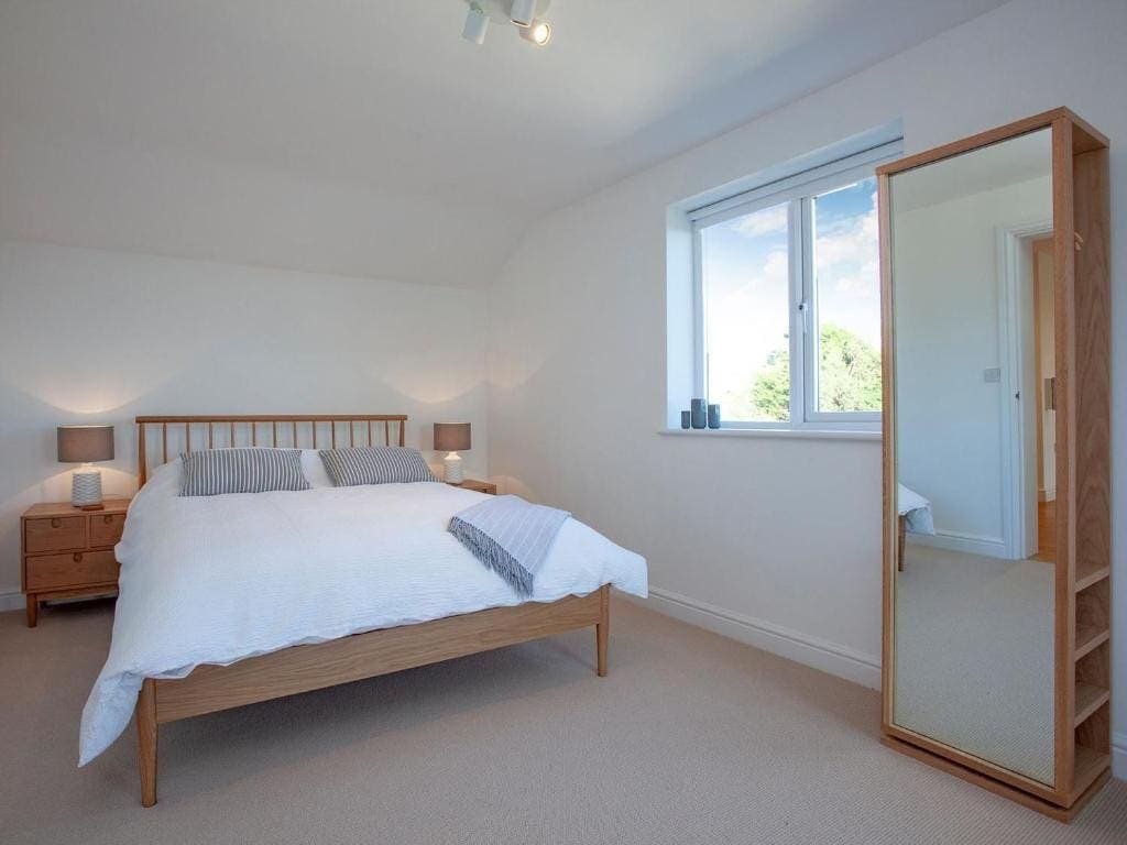 Bright bedroom with large bed, wooden furniture, open window