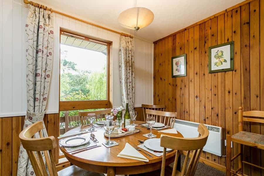 Cozy wooden dining room with set table and garden view