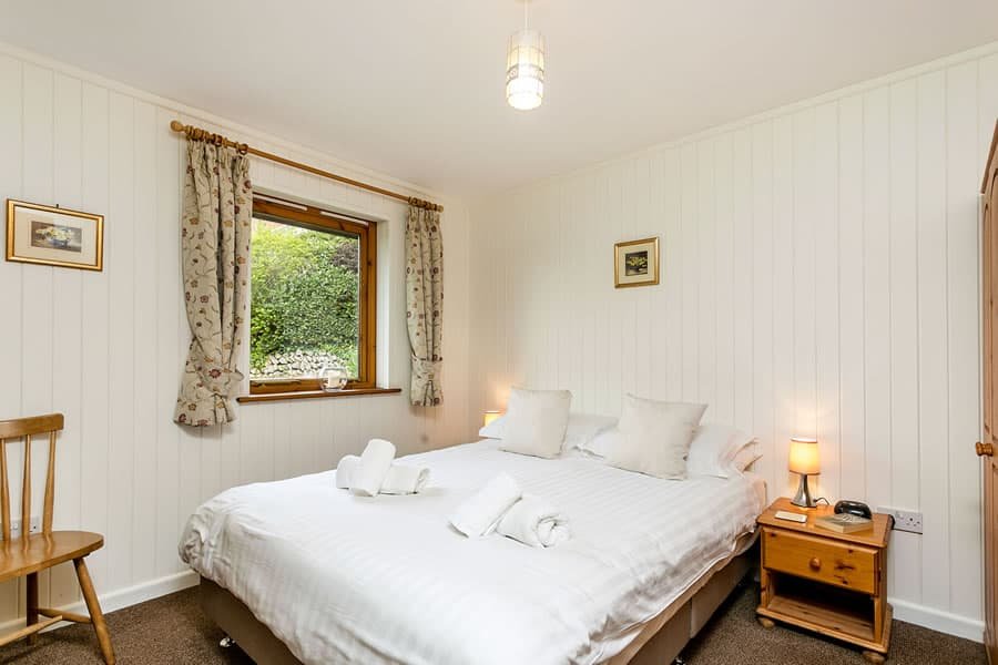 Cozy bedroom with white bedding and garden view window