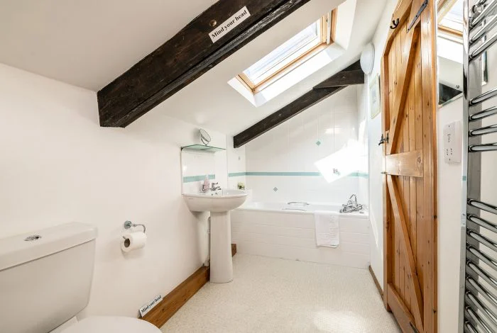 Bright attic bathroom with skylights and wooden beams
