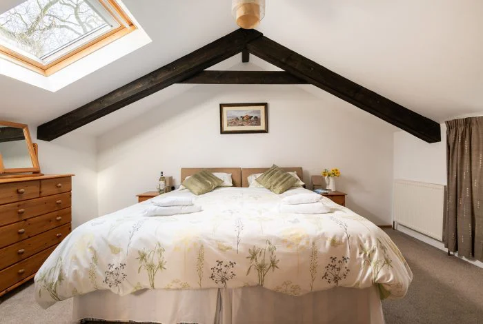 Cozy attic bedroom with exposed beams and skylight