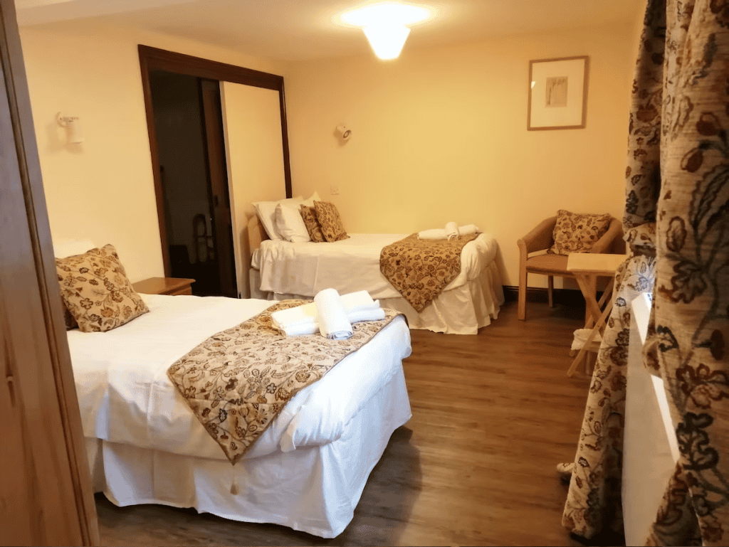 Bright hotel room with three beds and wooden floor