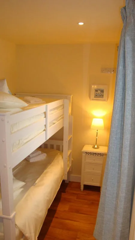 Cozy bedroom with white bunk beds and wooden floor