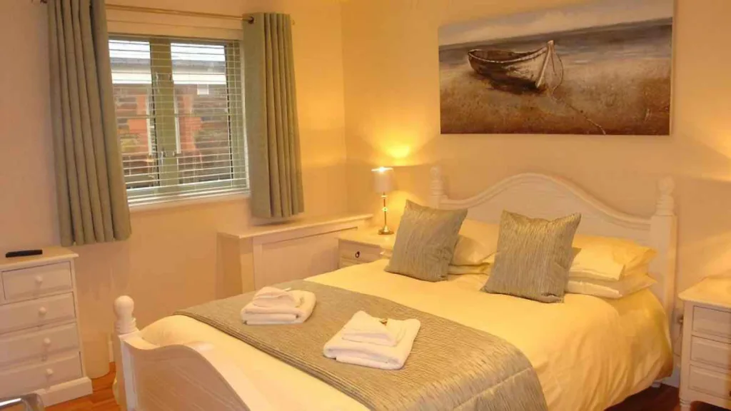 Cozy bedroom with white furniture and boat-themed artwork