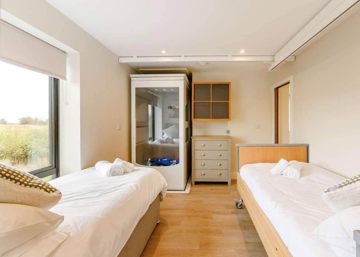Bright twin bedroom with open window and rural view