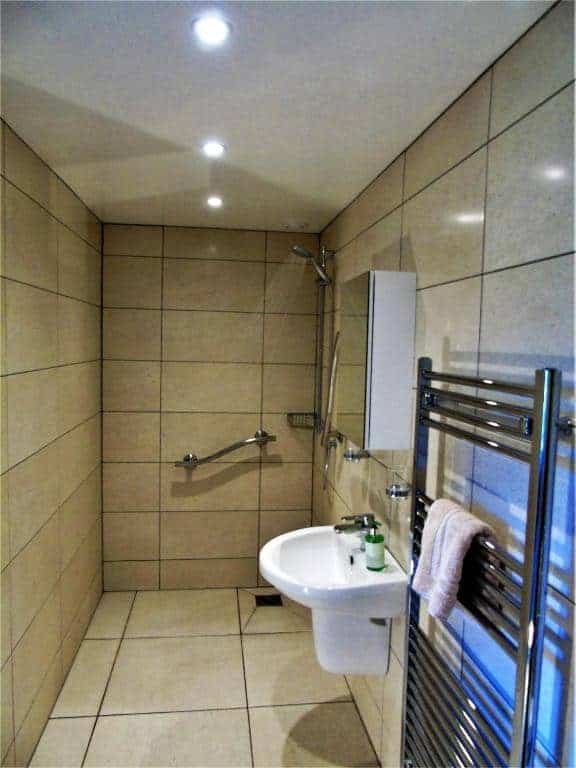 Modern beige tiled bathroom with shower and sink