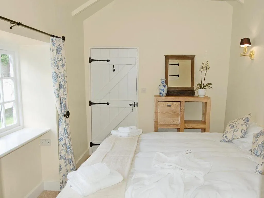 Cozy bedroom with white bedding and wooden furniture