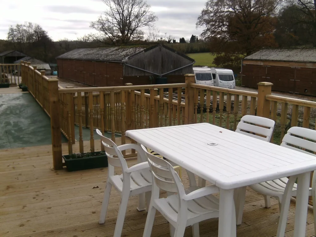 Rustic wooden deck with white table and chairs outdoors