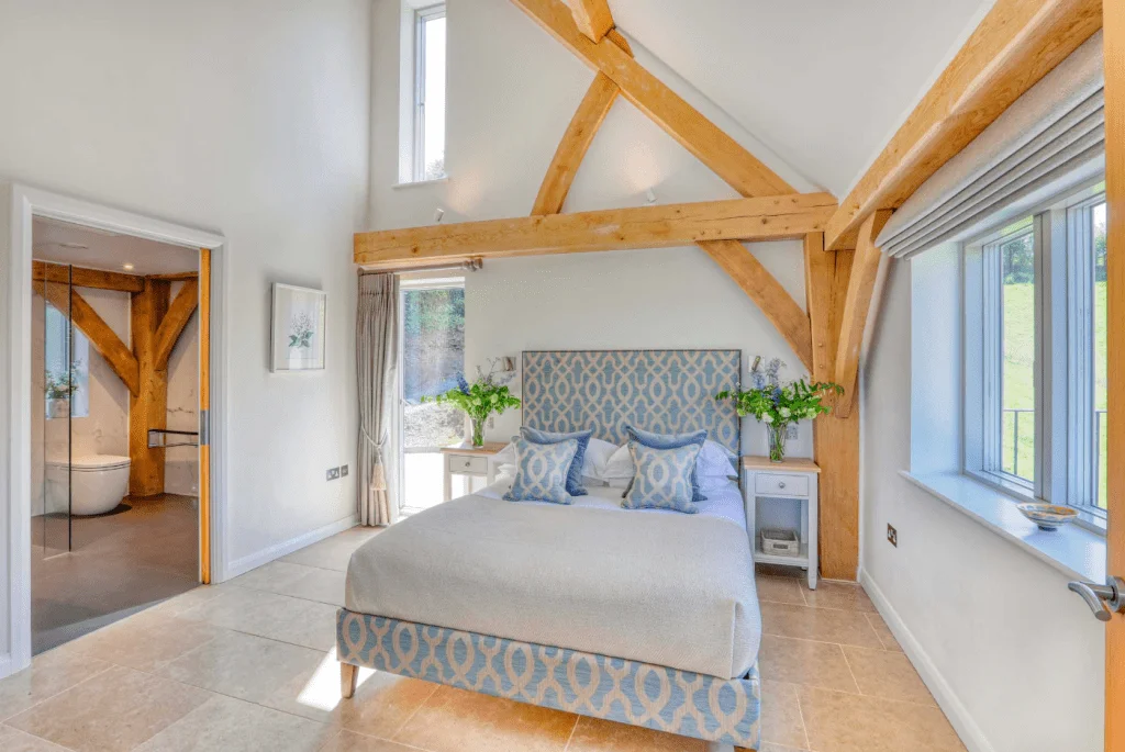 Spacious modern bedroom with exposed wooden beams and ensuite