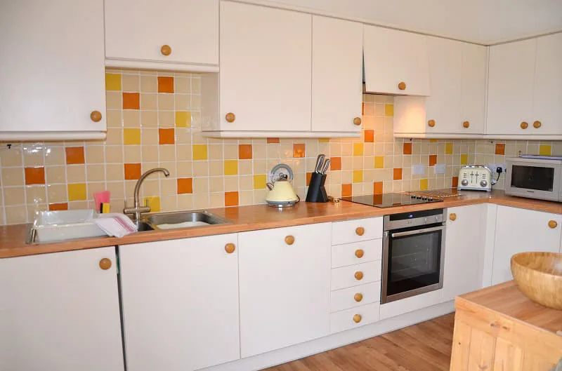 Bright kitchen with yellow tiled backsplash and white cabinets
