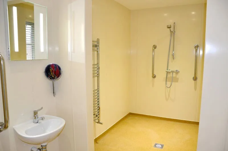 Modern bathroom with safety grab bars and yellow floor