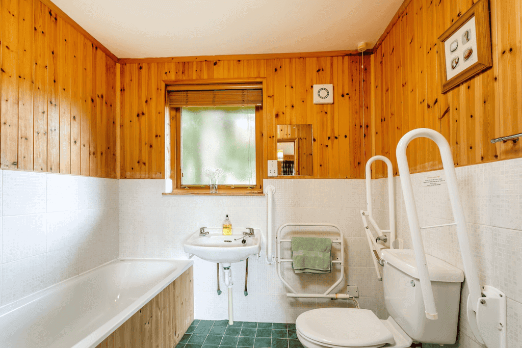 Accessible bathroom with wooden walls and white fixtures