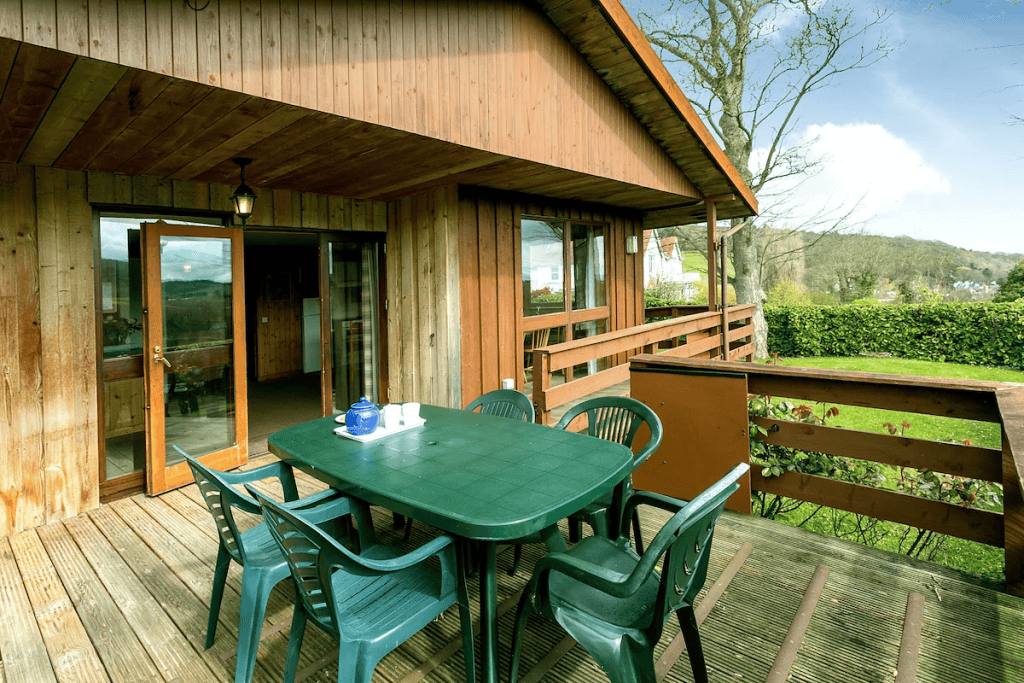 Wooden cabin porch with outdoor dining setup overlooking hills