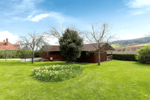 Rustic red cabin with daffodils in lush green landscape