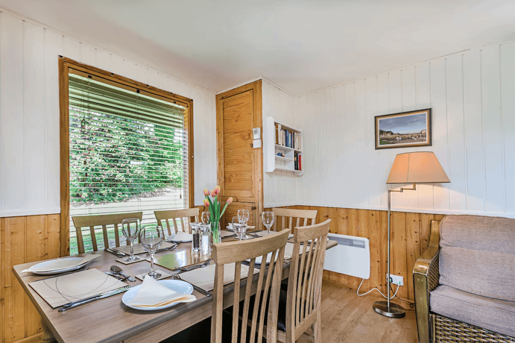 Cozy wooden dining room with set table and green view