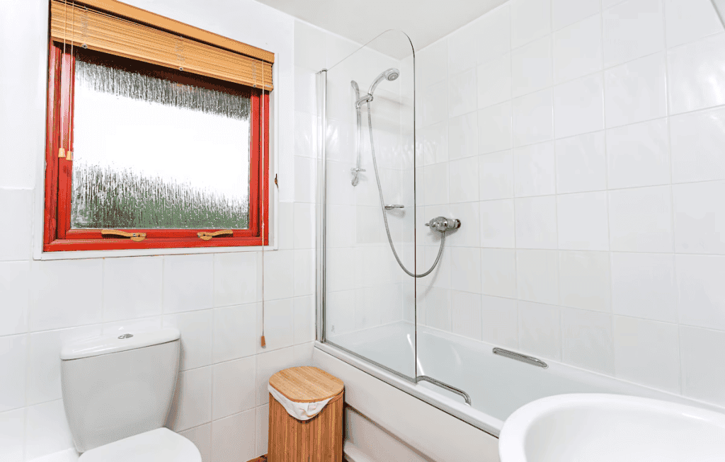 Bright modern bathroom with red window frame and shower
