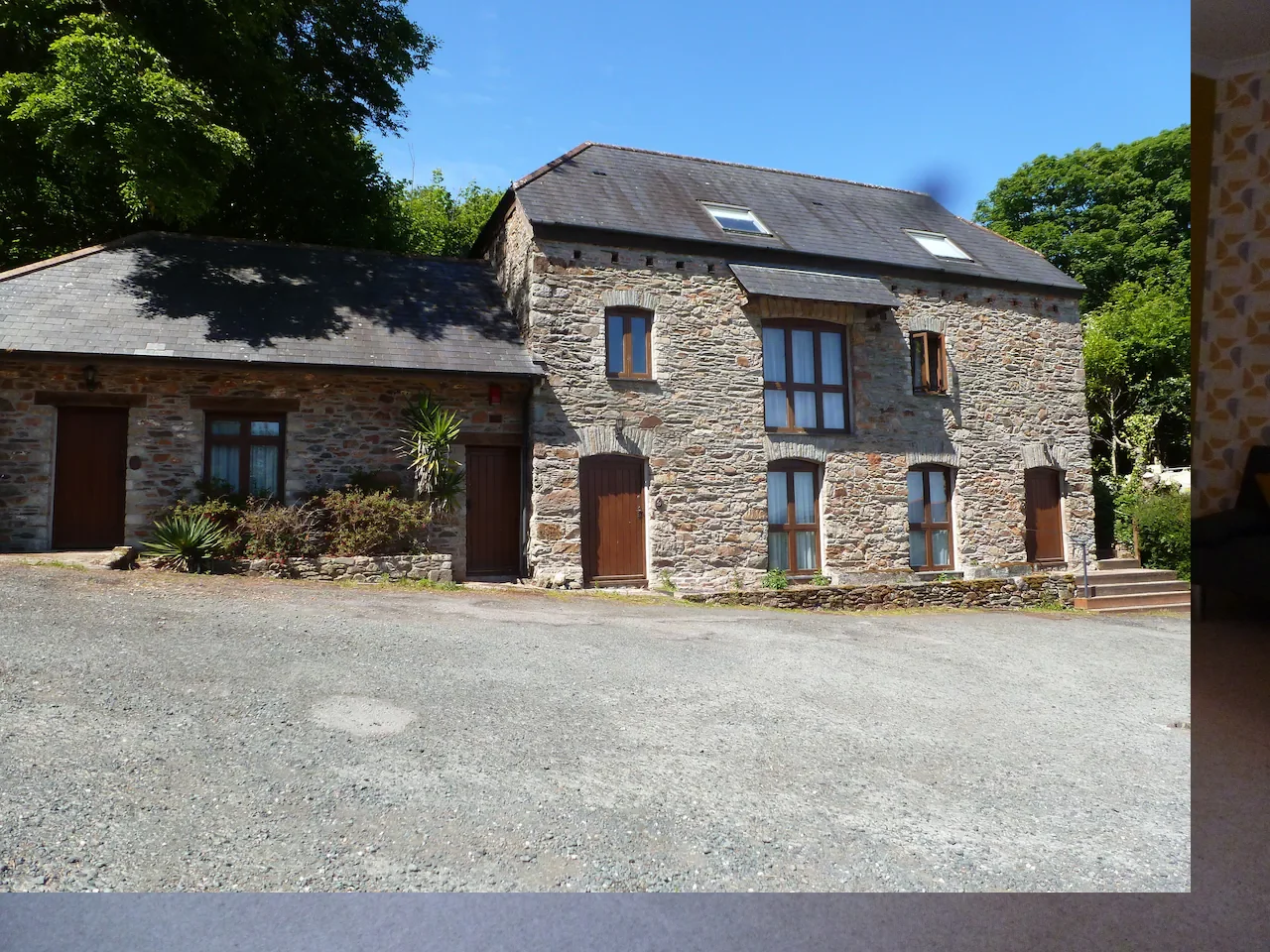 Stone building with blue windows in lush green setting