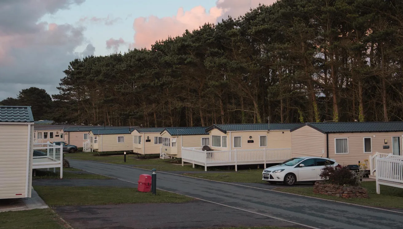 Caravan park with mobile homes and trees at dusk