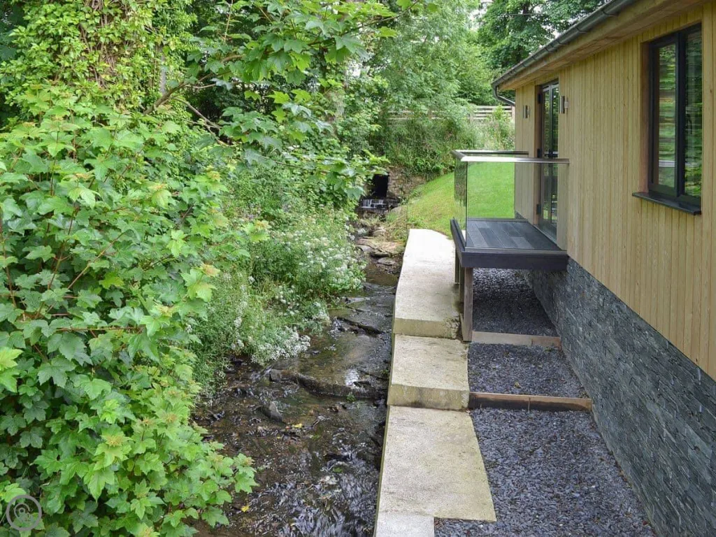 Streamside wooden cabin with lush green foliage