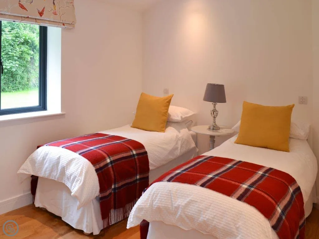 Twin beds with red plaid blankets in bright room