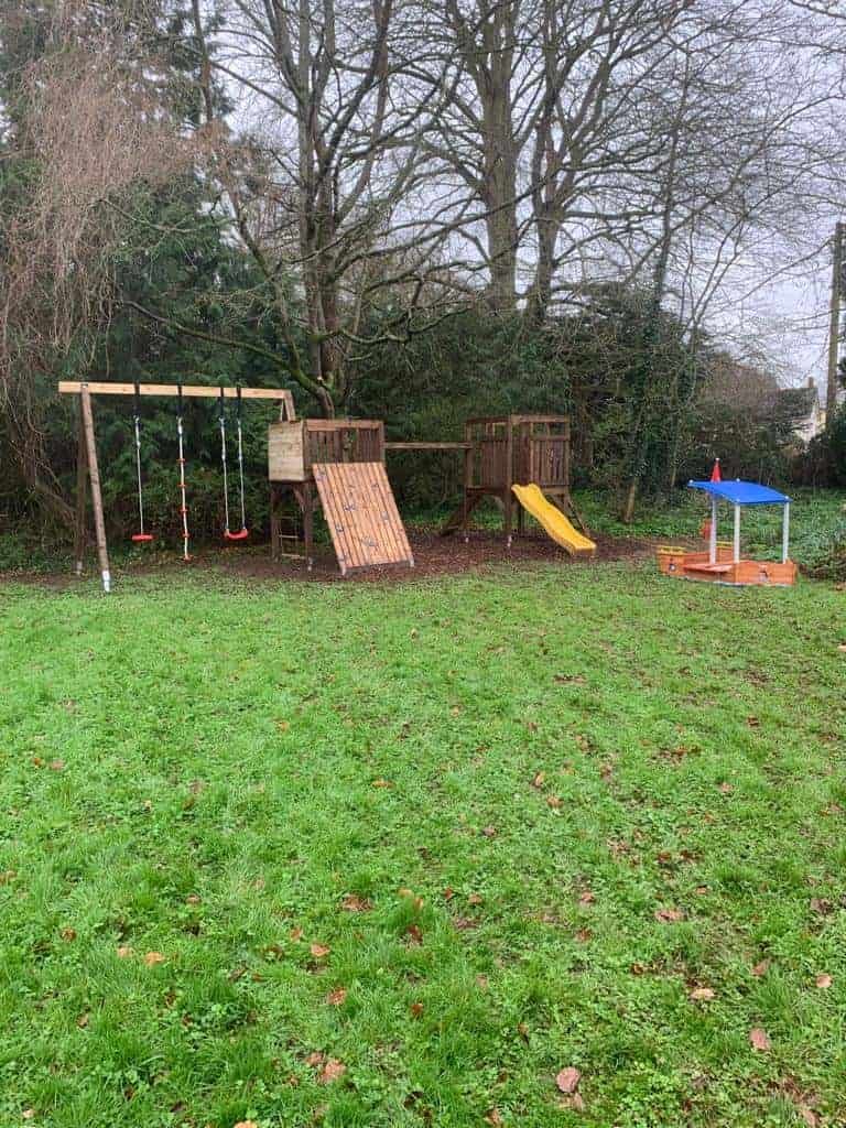 Playground with swings, slide, and sandbox on grassy area