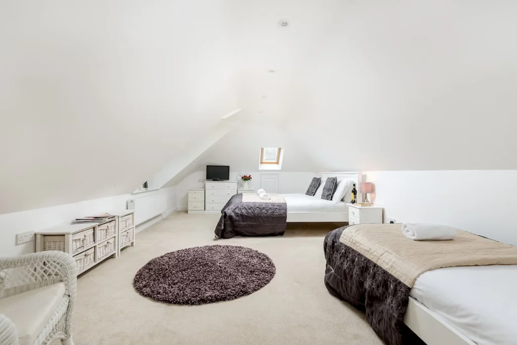 Spacious, bright attic bedroom with two beds and decor