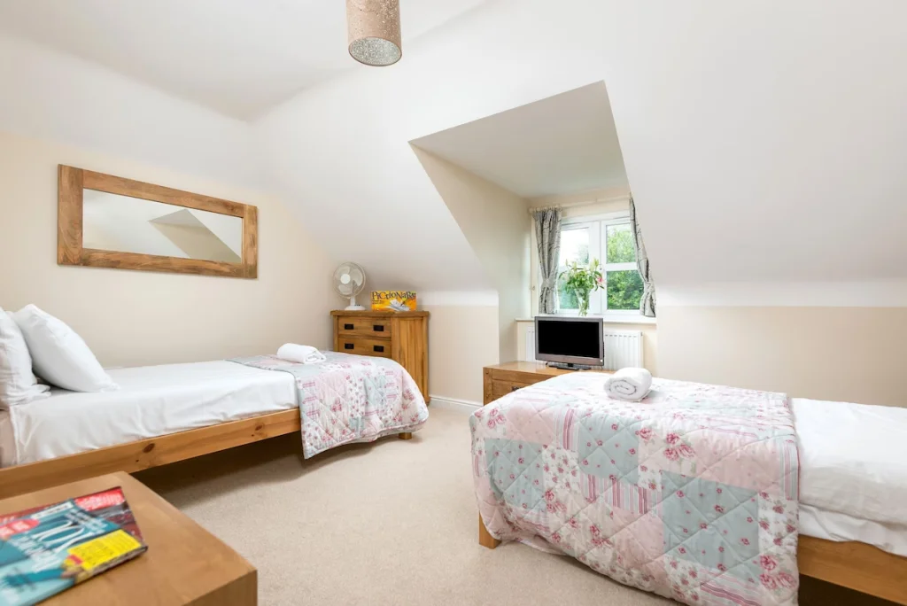 Bright twin bedroom with floral bedding and wooden furniture.