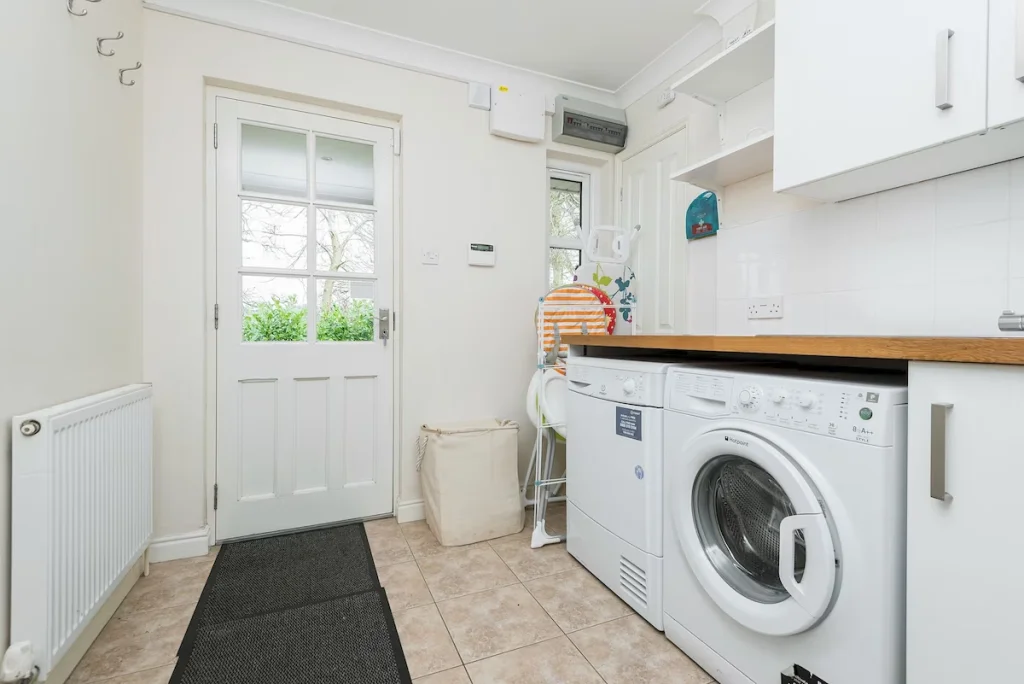 Bright laundry room with white appliances and front door