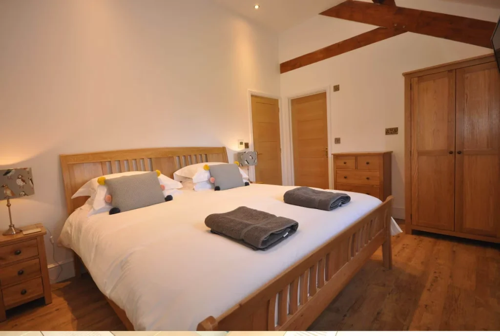 Cozy bedroom with large bed, wooden furniture, and beams