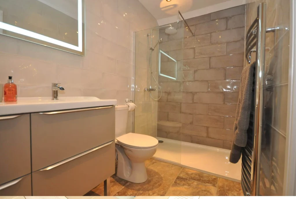Modern bathroom with shower, sink, toilet, and mirror.