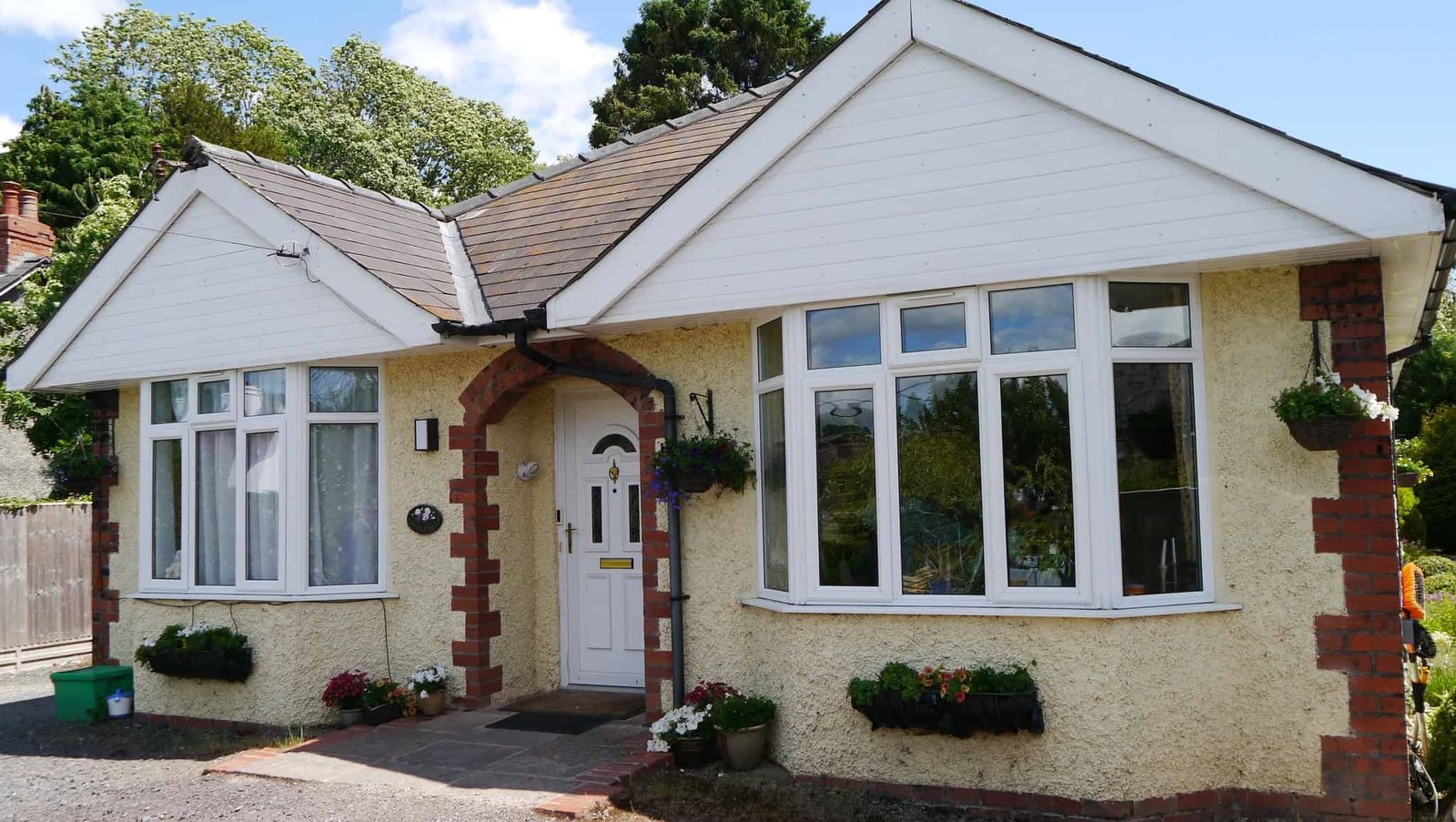 Charming white cottage with lush greenery and flowers