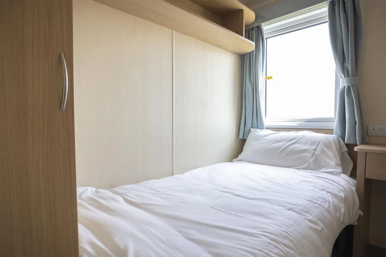 Compact modern bedroom with white bedding and window