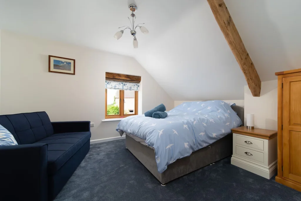 Cozy attic bedroom with wooden beams and countryside view.