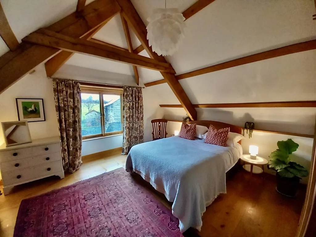 Cozy attic bedroom with exposed beams and garden view