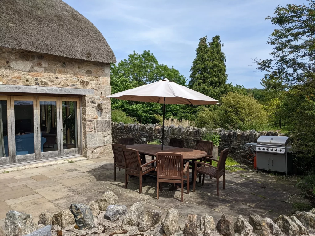 Stone patio with dining set, umbrella, and barbecue grill