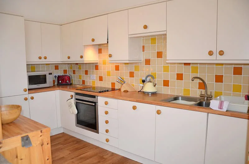 Bright kitchen with yellow tile backsplash and white cabinets