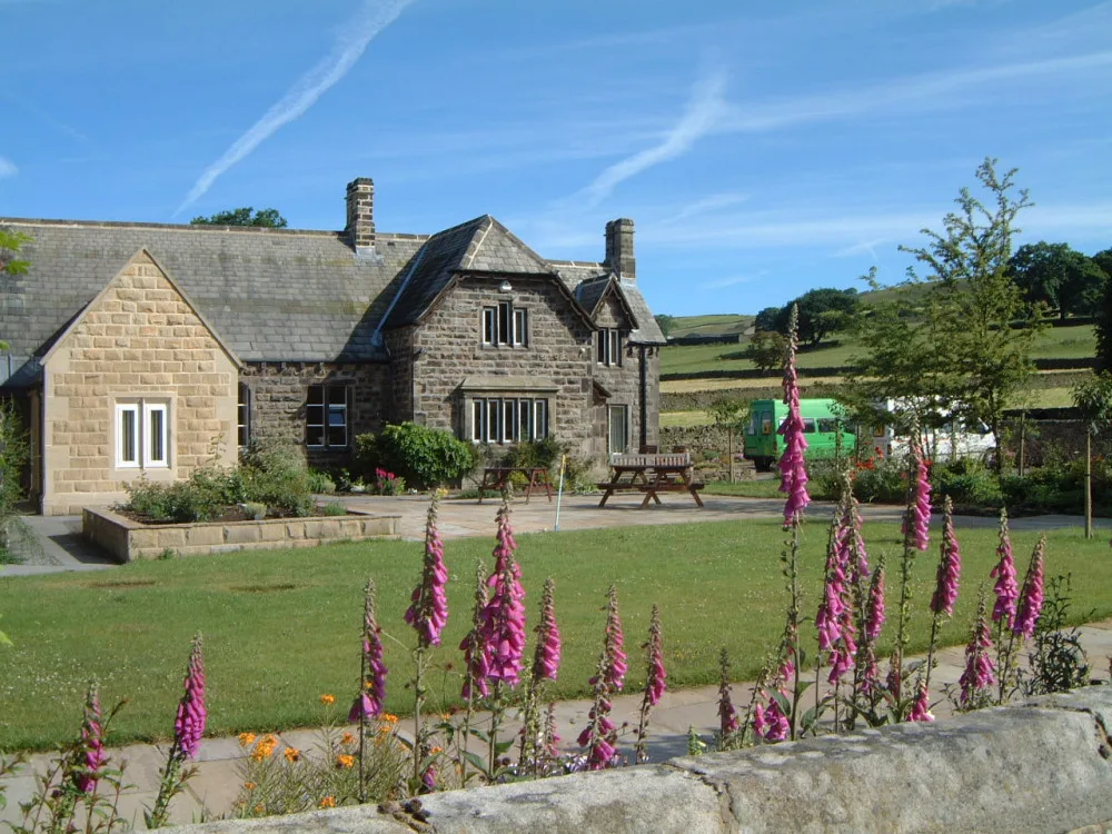 Stone house with vibrant pink flowers in front.