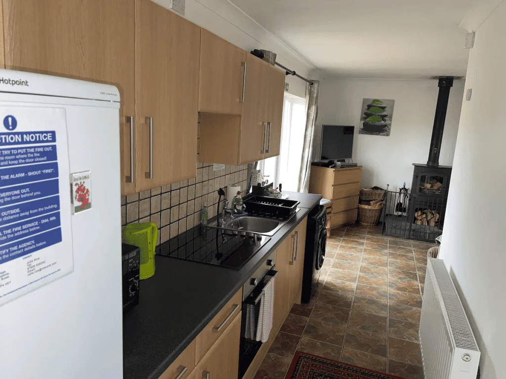 Long kitchen with wooden cabinets and black stove.