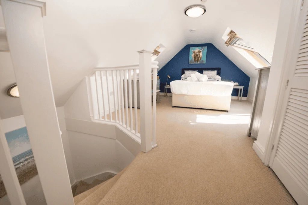 Bright attic bedroom with blue walls and white bed