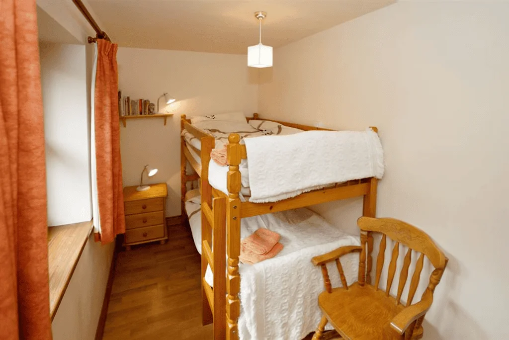 Cozy wooden bunk bed and rocking chair in small room