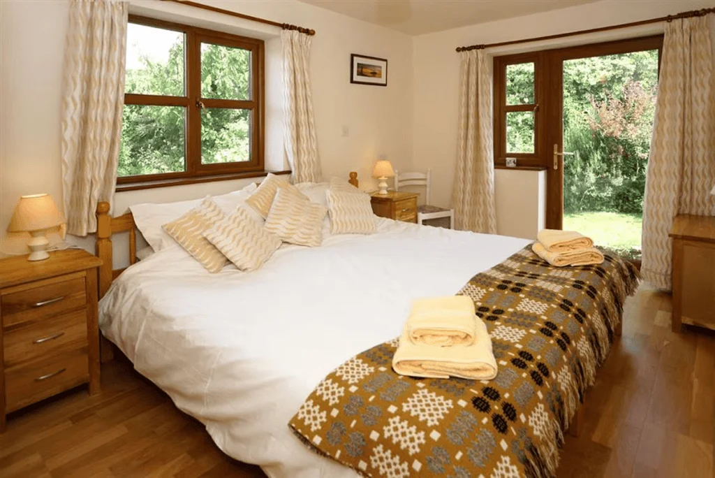 Cozy bedroom with bed, windows, and forest view
