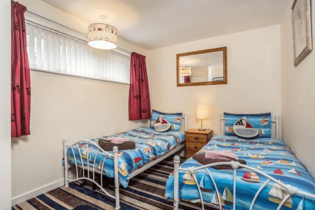 Bright nautical-themed twin bedroom with striped rug
