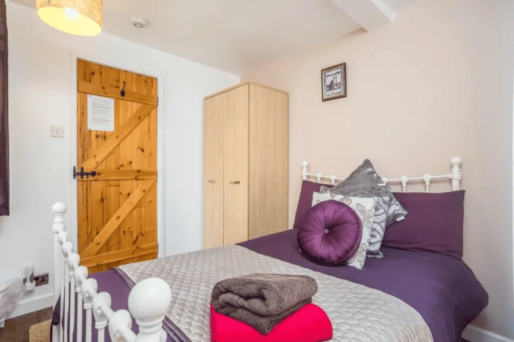Cozy bedroom with purple bedding and wooden door
