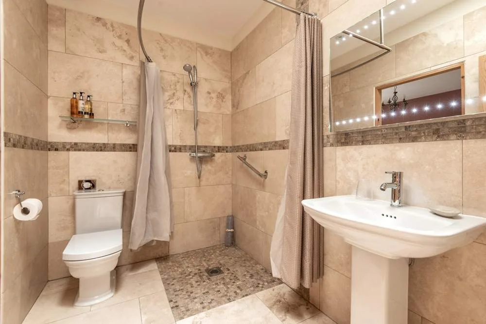Modern beige tiled bathroom with shower and mirror