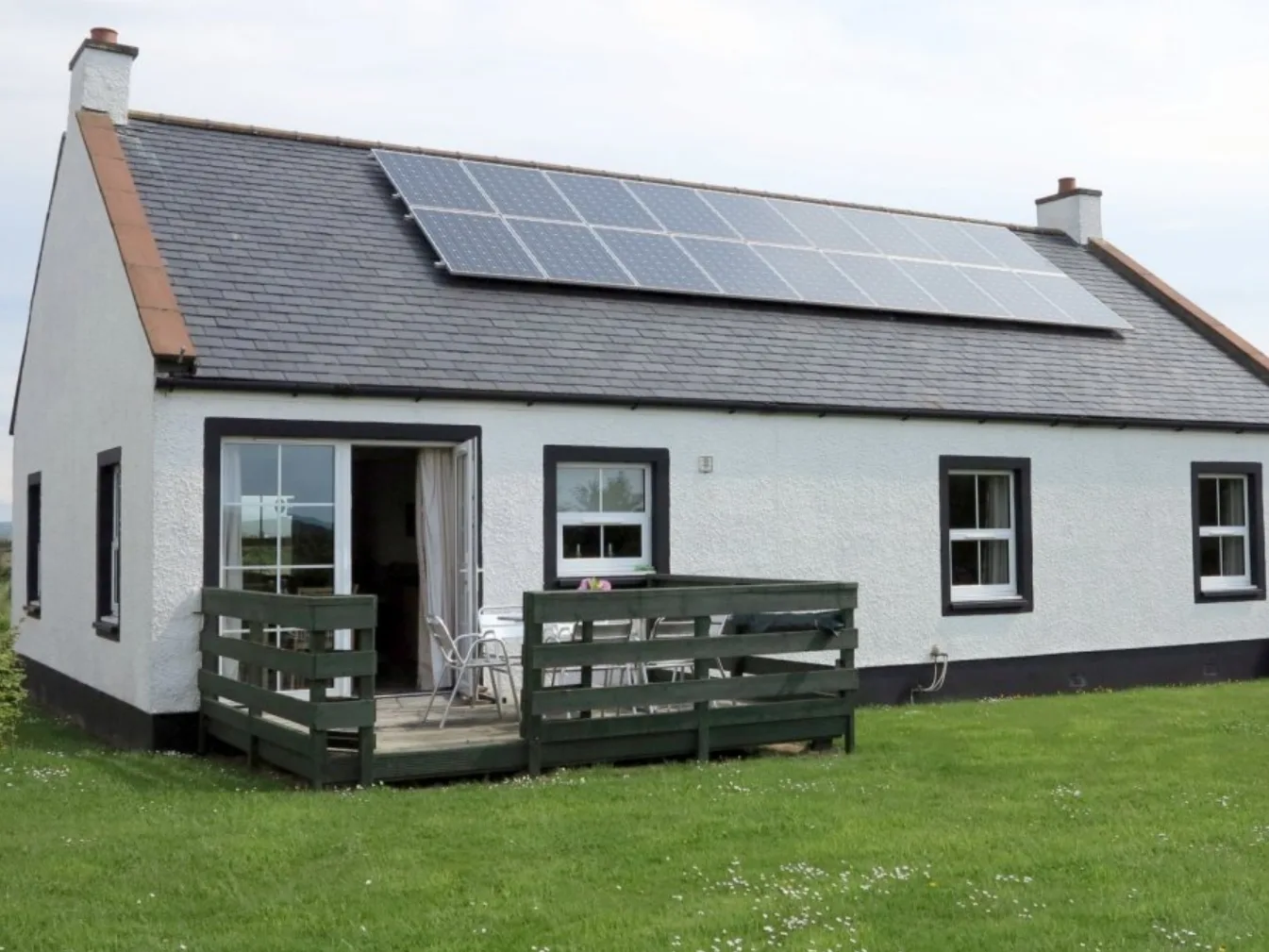 Cottage with solar panels and green lawn