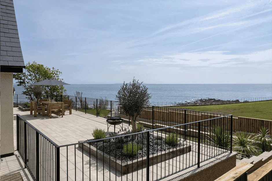 Coastal patio with ocean view, furniture, and greenery
