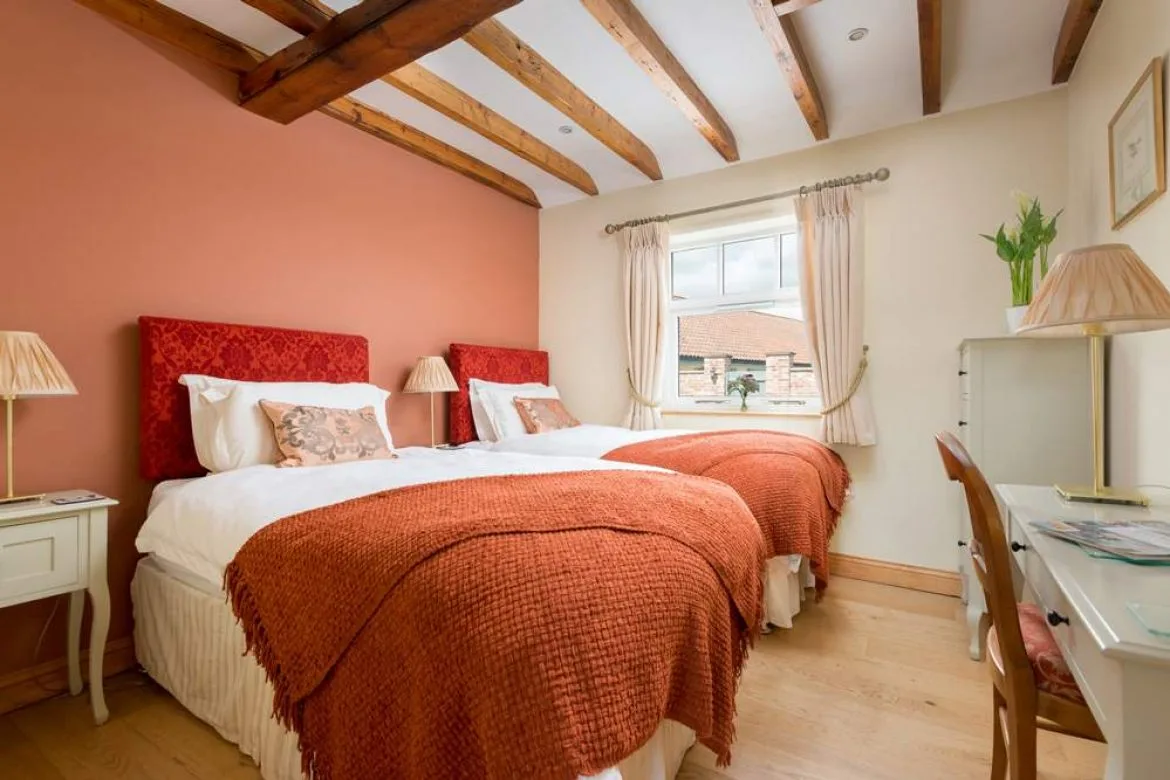 Cozy twin bedroom with exposed wooden beams and orange decor