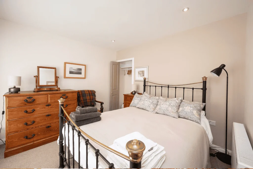 Cozy bedroom with iron bed frame and wooden dresser