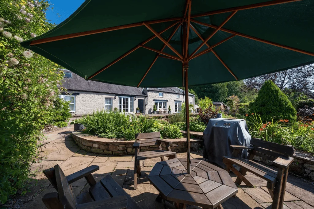 Sunny garden patio with umbrella and lush greenery